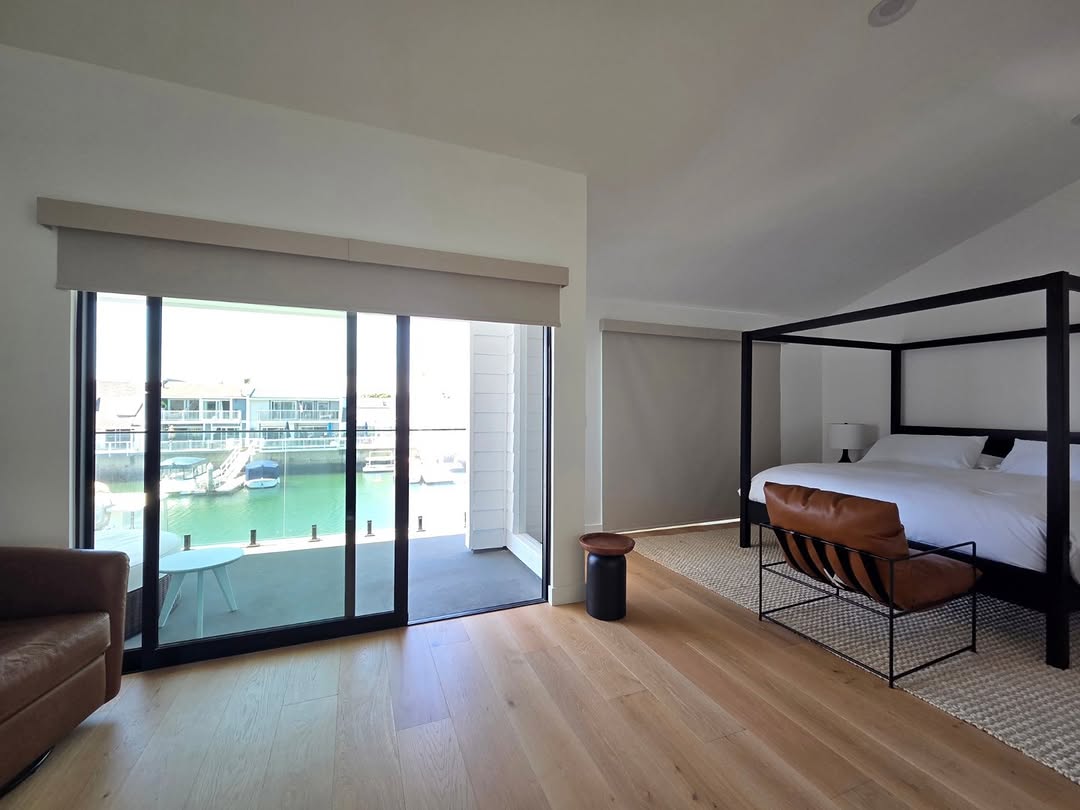 Waterfront bedroom with blackout roller shades in fabric-wrapped valances over sliding glass doors